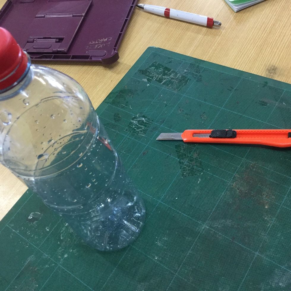 While you wait for the paint to dry, find a plastic bottle from around the house and cut it into 2 parts using an exacto knife