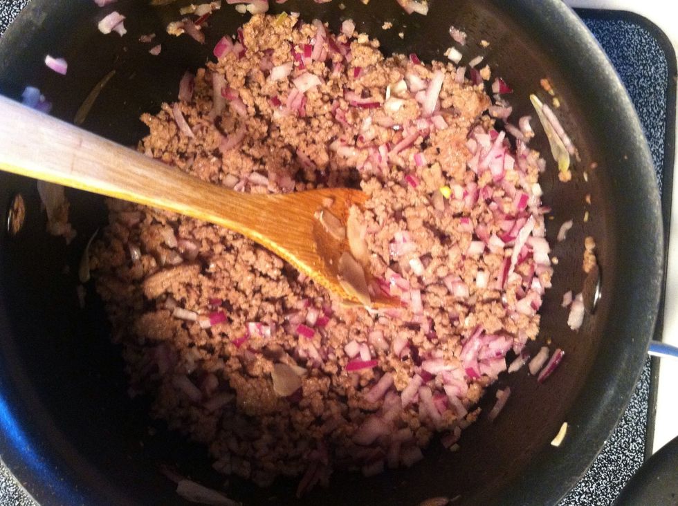 While your meat is still cooking, mix in the onion and finely chopped garlic cloves.