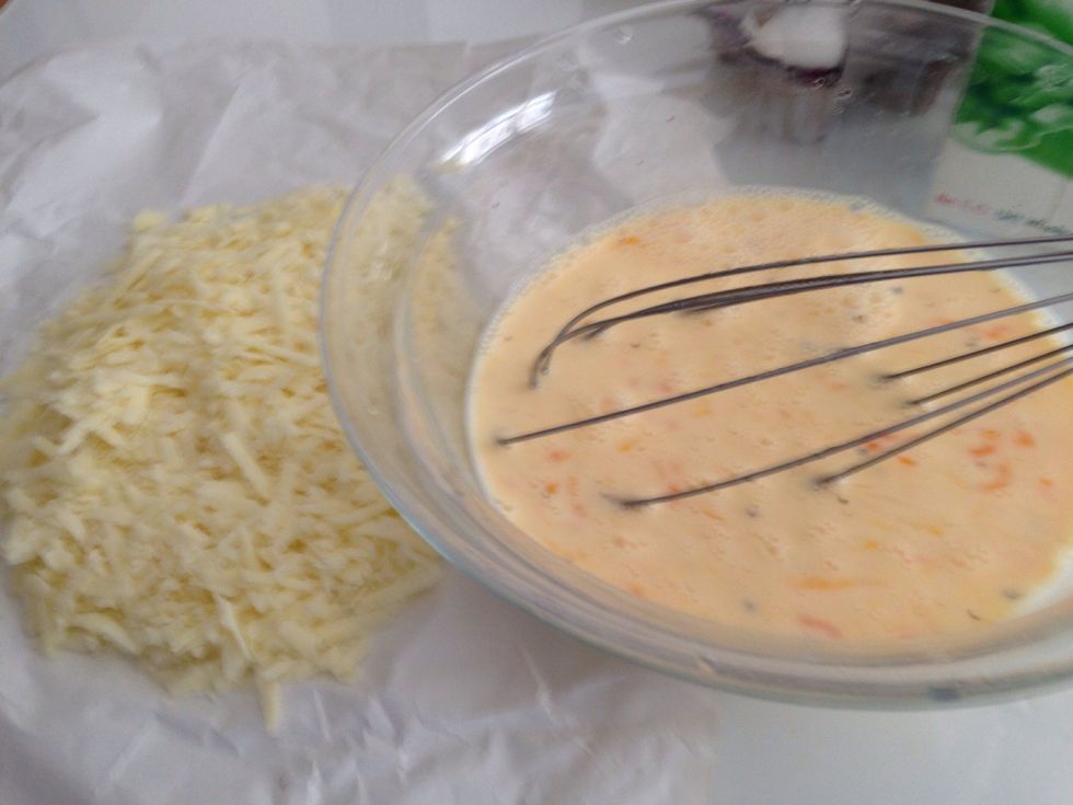 Whilst the dough is baking add 4 eggs and 1 cup of milk to a bowl and whisk. Add pepper and 250g of grated cheddar cheese. TIP: Add more or less cheese depending on your taste.