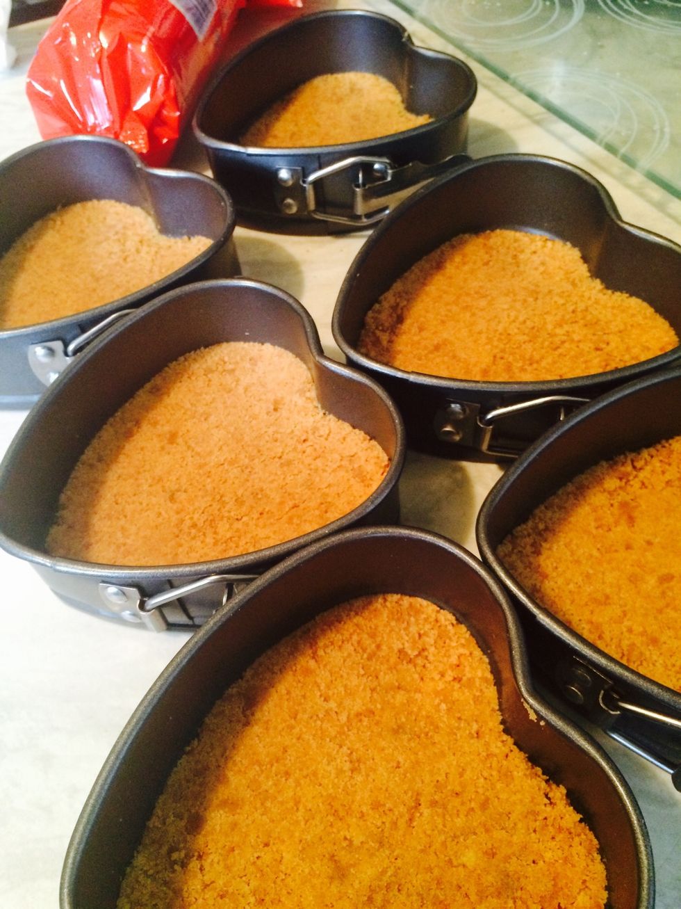 Whilst the topping mixture is mixing, spoon the biscuit crumbs into your baking tin. Level it for a smooth finish.