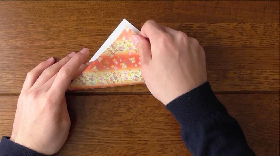 White side up, fold in half diagonally.  Fold right corner to the left.