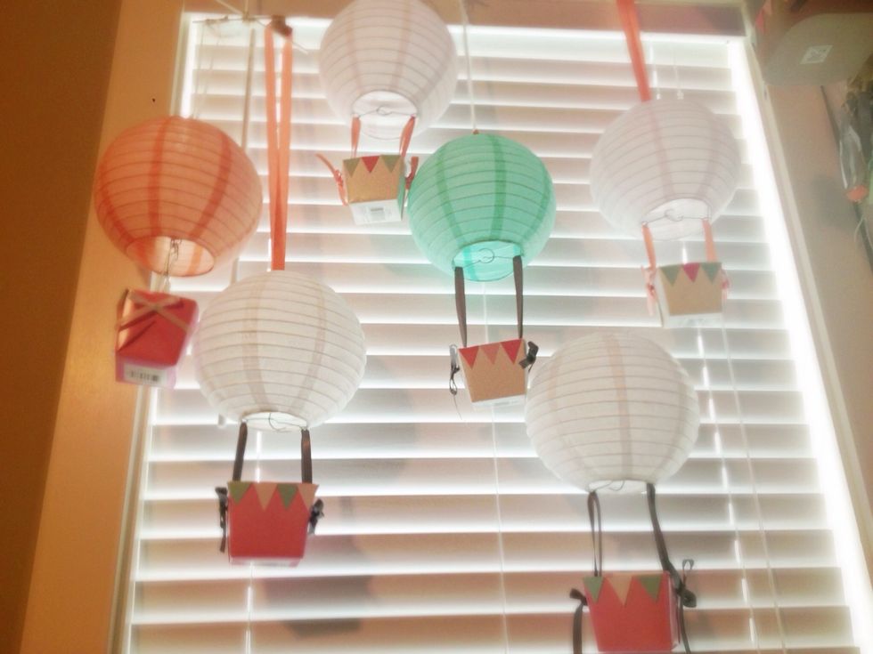 With 2 equal lengths of ribbon, turn lantern upside down and weave ribbon over the wire of lantern, pull both ends through the holes on the side of the box, tie bow or knot to secure