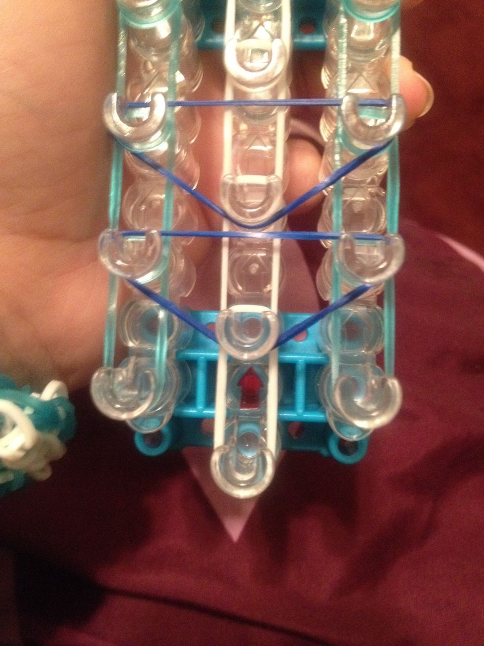 With a color of the rubber bands make d's . But skip the first three pegs. Do the until u reach the starburst