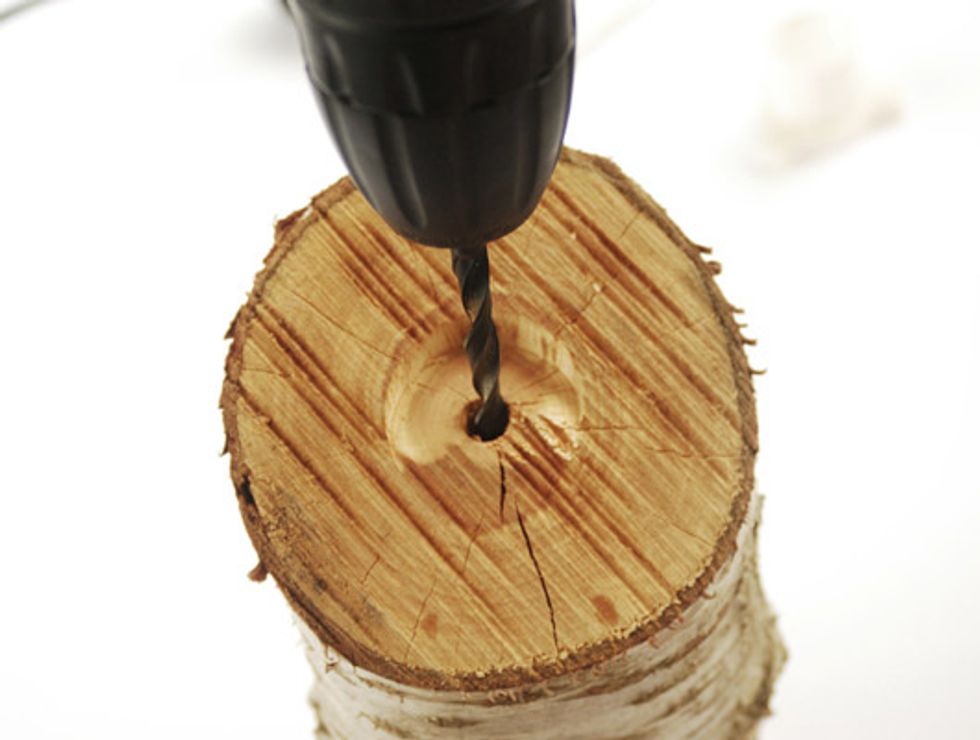With a drill for wood drill a hole in the center of the log