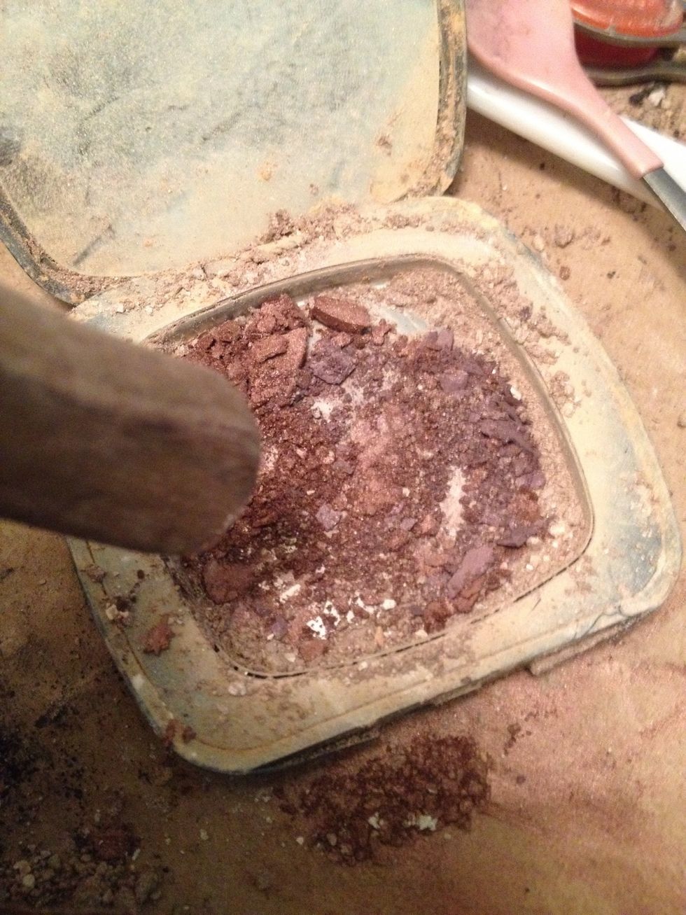With a knife, scrape the eyeshadows that can't be depotted into an old compact. Crush hard shadows with knife bottom, mix with fork, add oil, and pack into tins.  Press down hard with spoon.