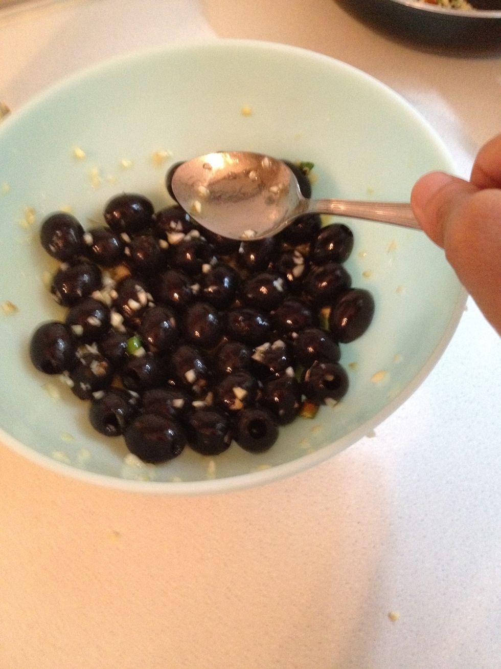 With a spoon to try to make the olive lay on the oil as much as you can. It will absorb the oil and will develop a richer taste.