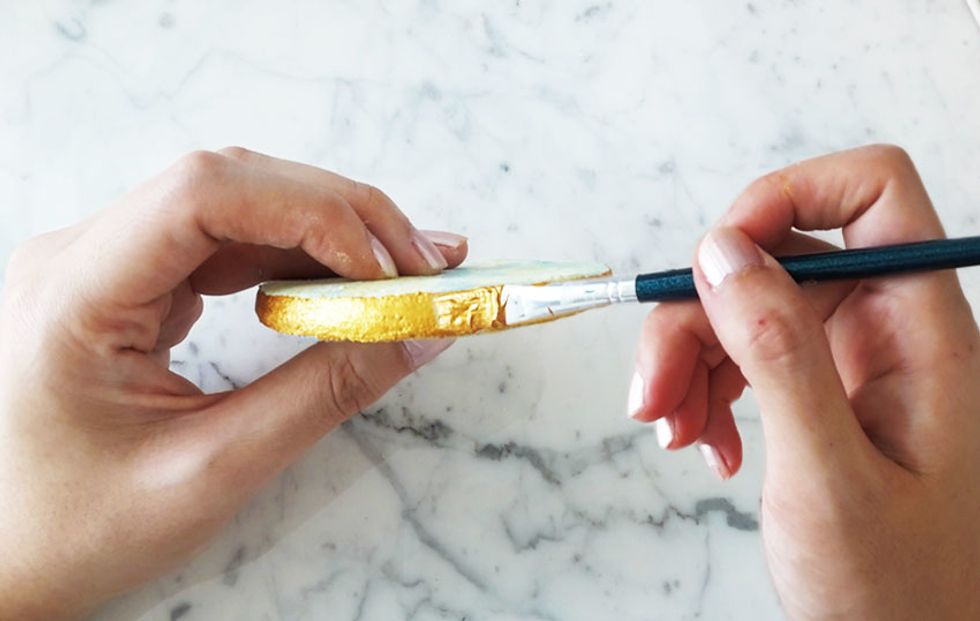 With a thin paintbrush, coat the sides of the coaster with gold paint. Apply a second layer if necessary, once first layer is dry.