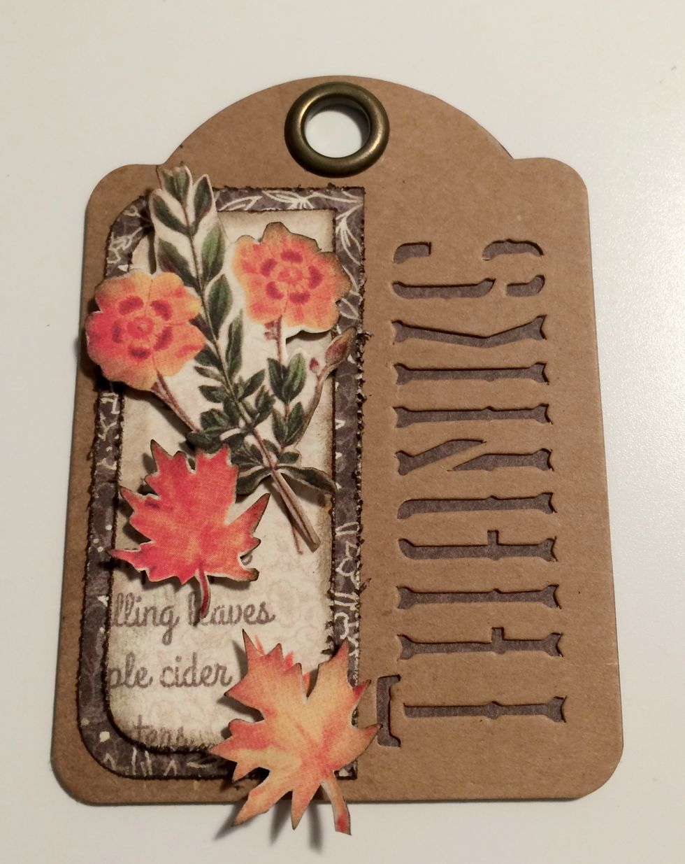 With a third brown thanks tag, foam square the floral piece to the top of the fall paper. Foam square the two leaves randomly overtop of the fall paper.