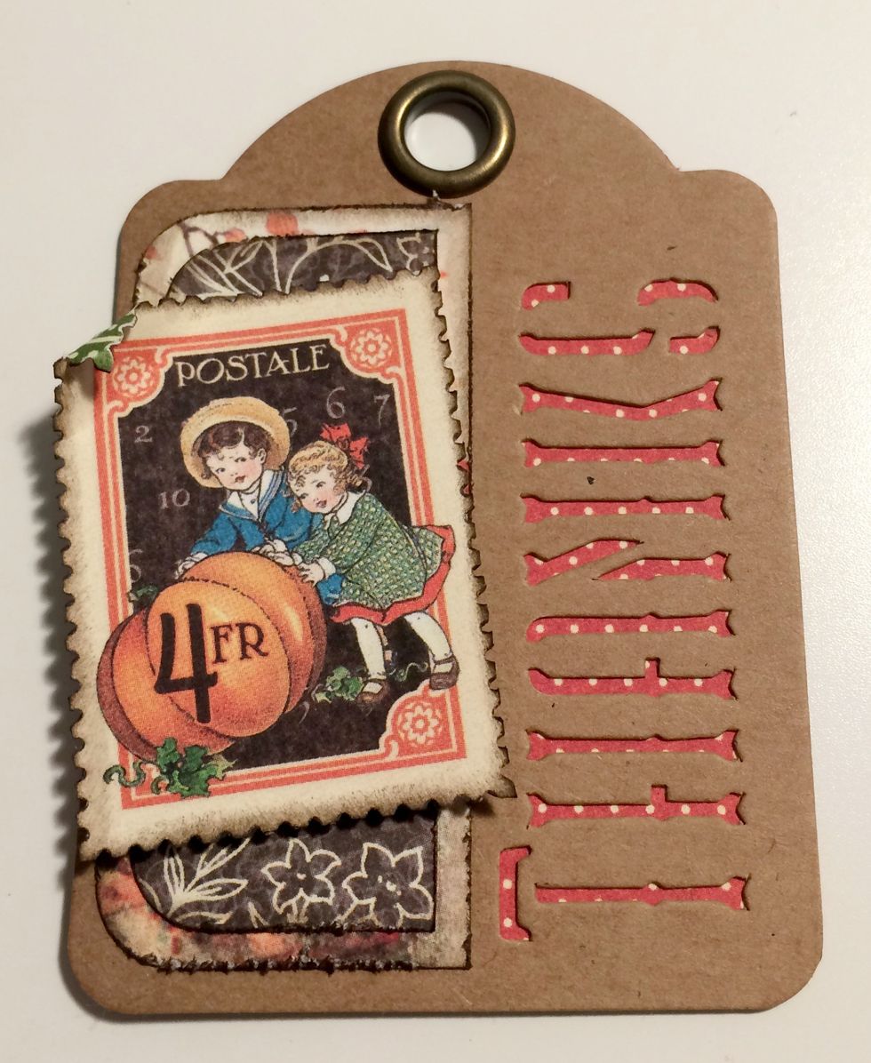 With a third red dot thanks tag, foam square a stamp on an angle overtop of brown floral piece. Roll the top left corner down.