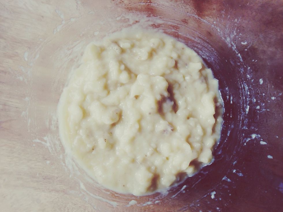 With a wooden spoon, mix butter into the mashed bananas in a large mixing bowl.