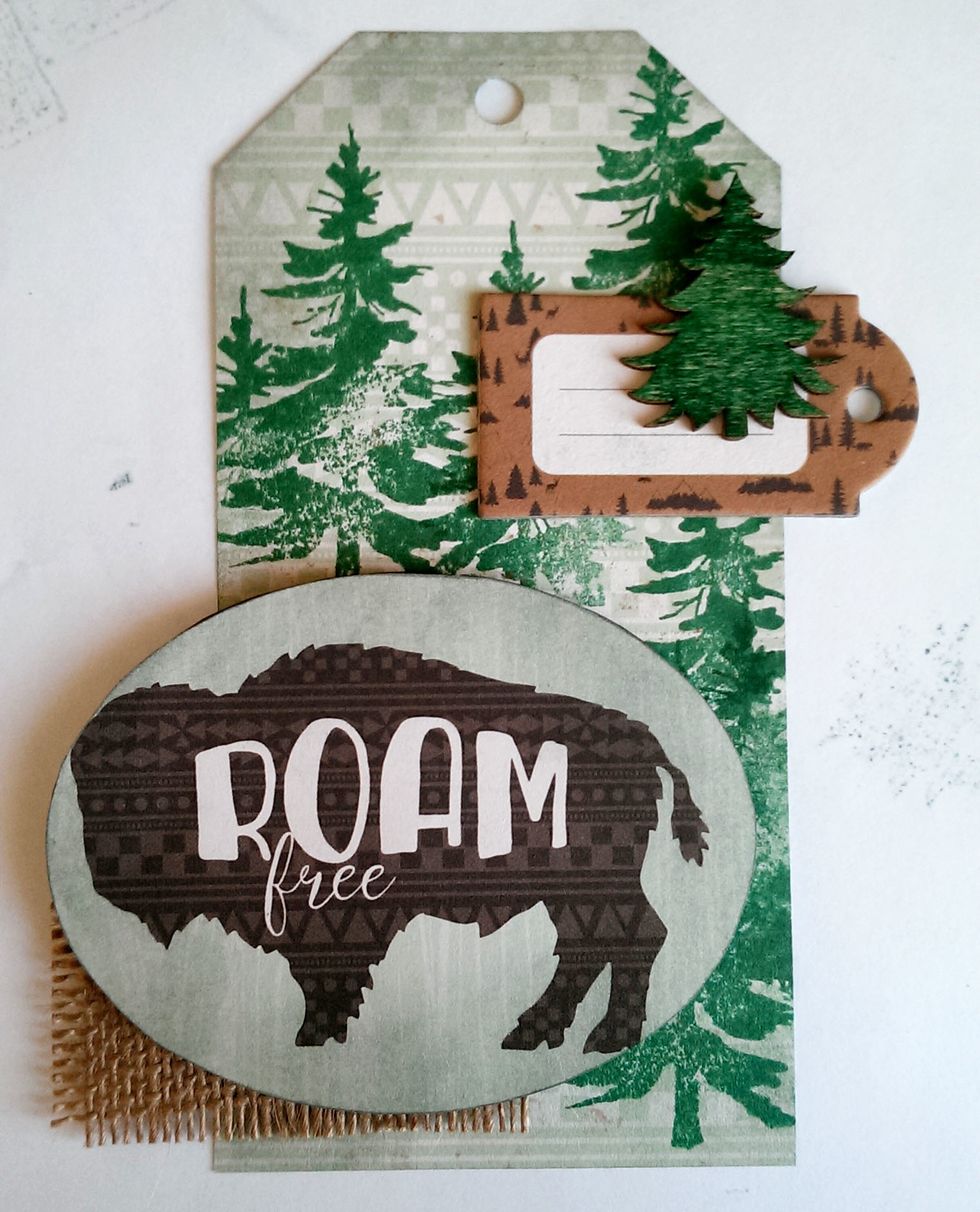 With double sided tape, secure a small piece of burlap in the bottom left corner. Add a couple more 3D Foam Dots to the back of the Buffalo Oval, and secure that to the top of the burlap.