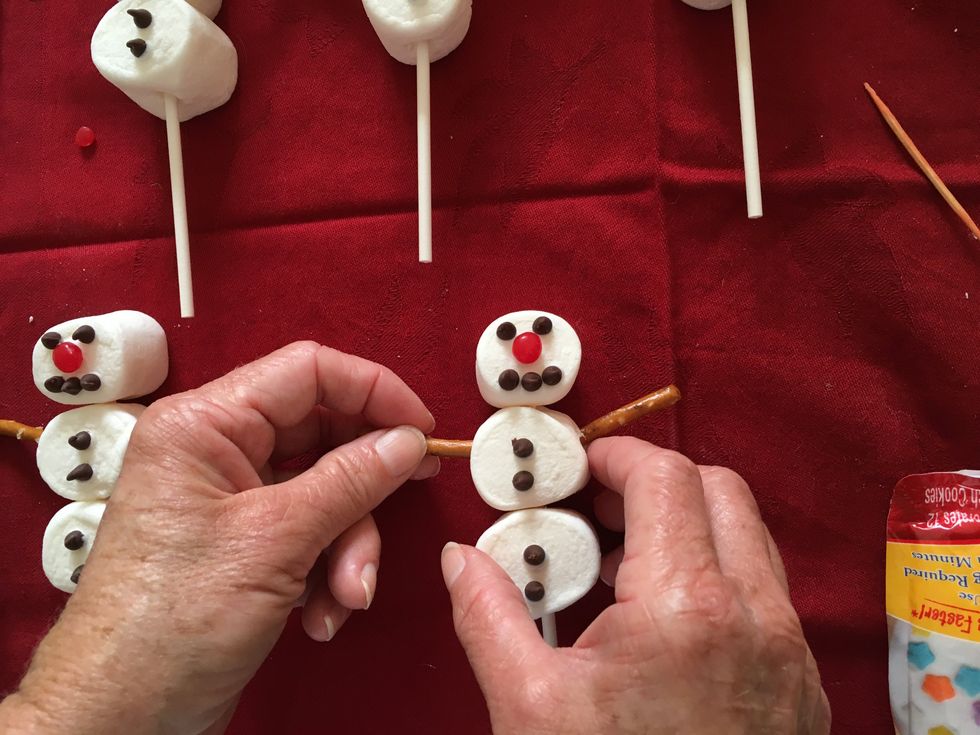 With icing stick on mini chips to make buttons.  Then break the pretzel sticks in half and poke into the body marshmallow body.