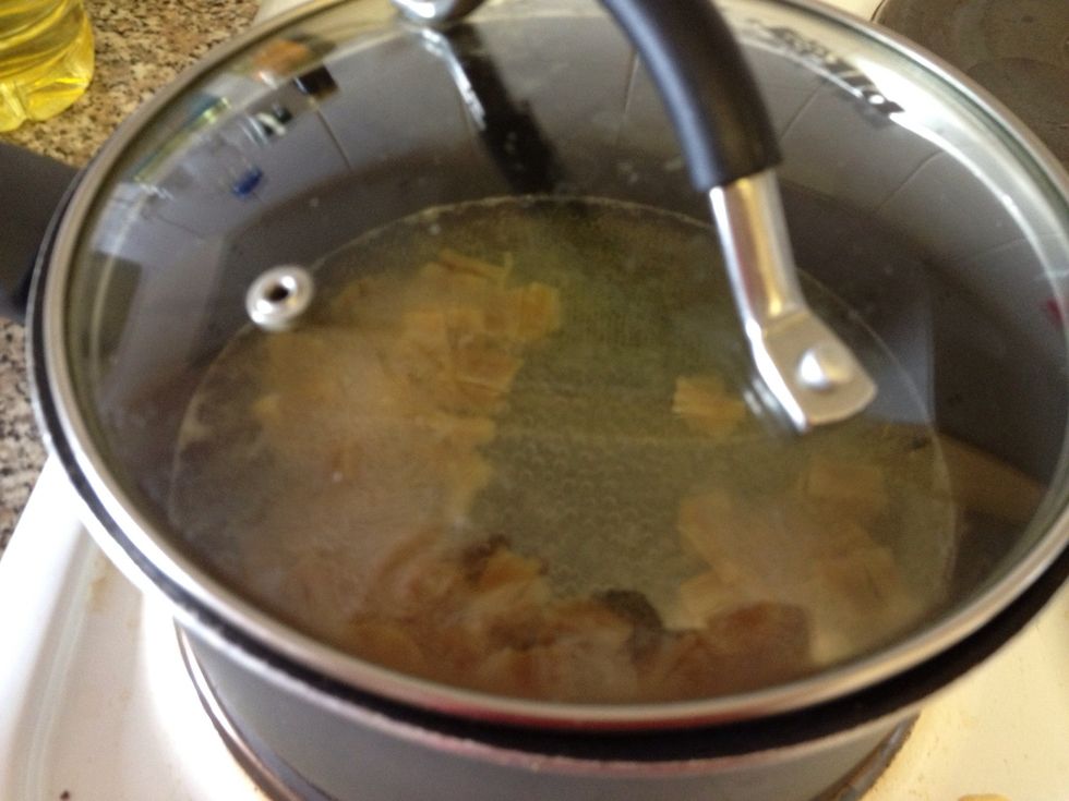 With lid on. Let it boil to soften the scallop and sweeten the soup. Watch out for the amount of water left as it boils. Make sure the level of water always covers the scallops. Leave at medium heat