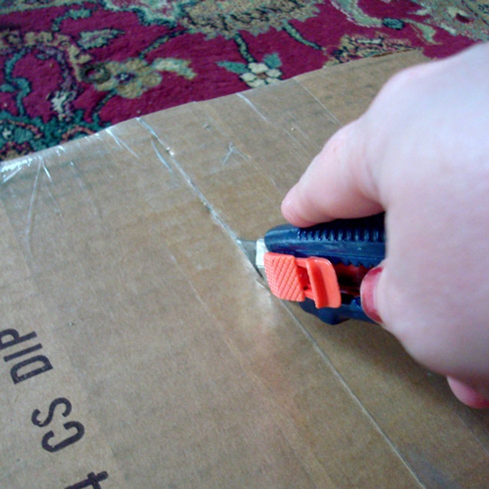 With my boxcutter I slice the sealed box in half...