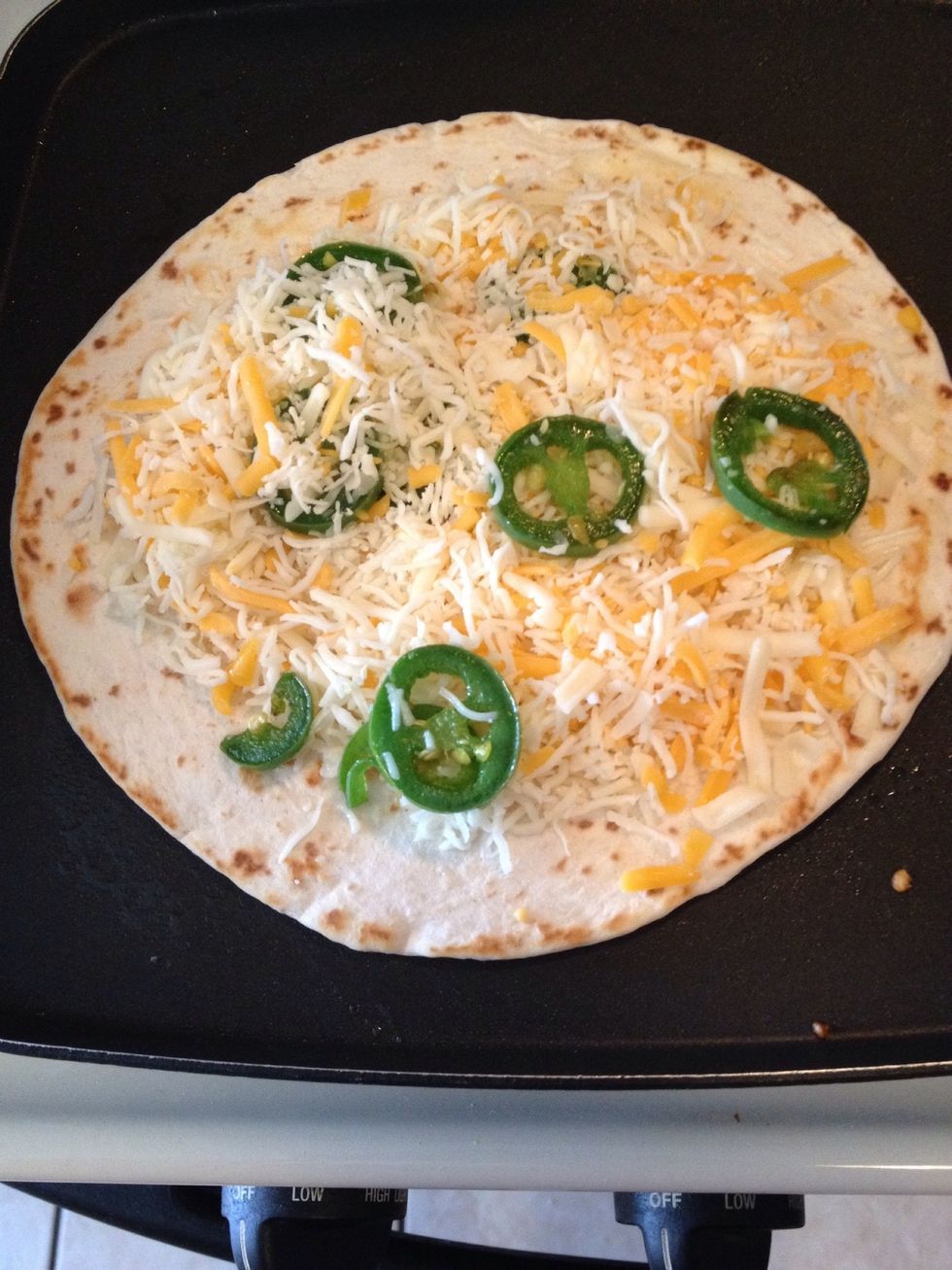 With one tortilla on skillet add cheese and jalape\u00f1os