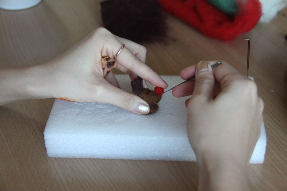 With red wool, form a giant red nose and attach it to the head, too.