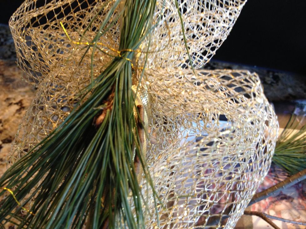 With the ends of the wire that are left on the hoop, secure some small sprigs of pine onto the mesh.