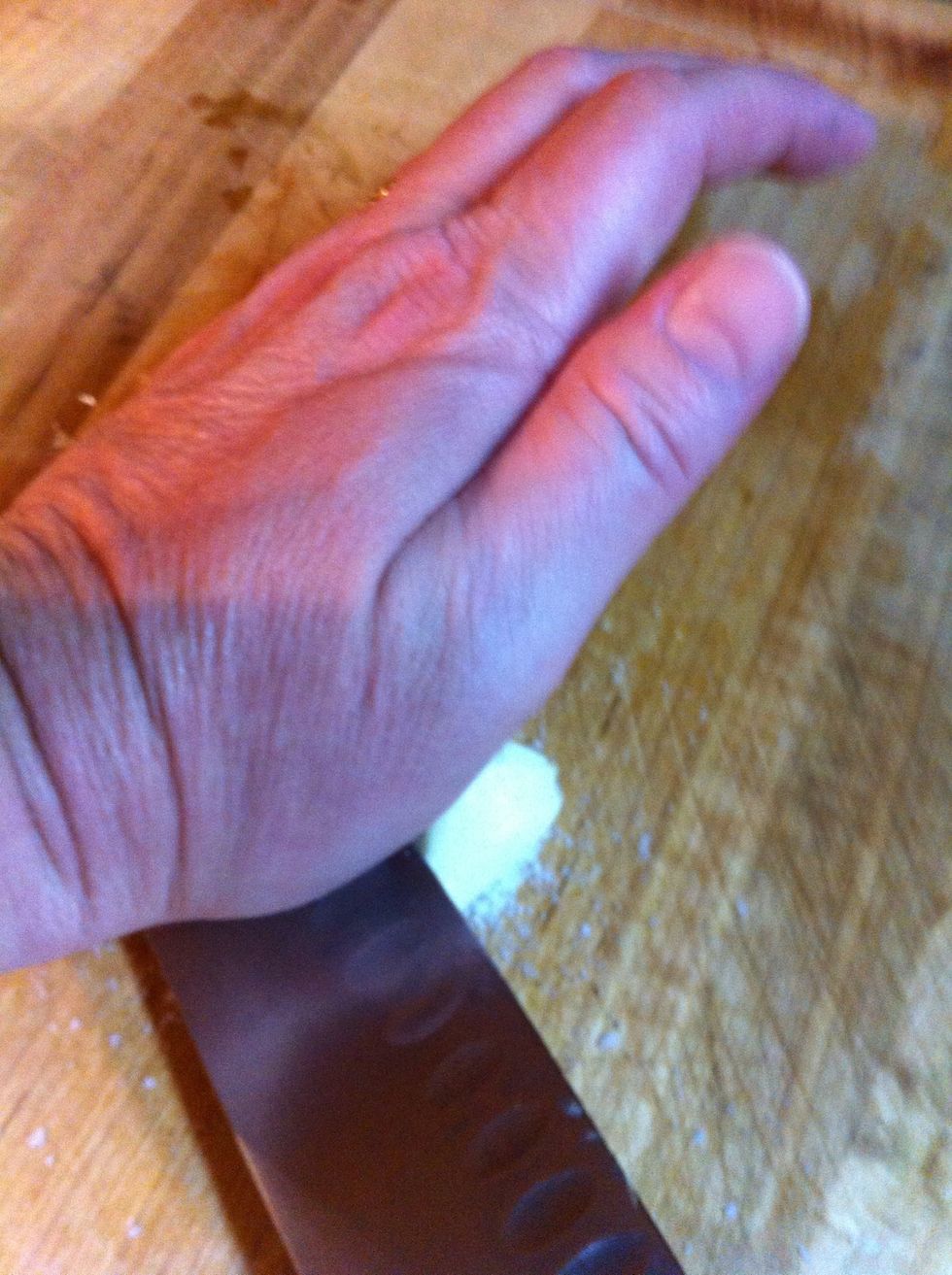 With the heel of your hand on knife's edge, mash the salt and garlic infusing the two.