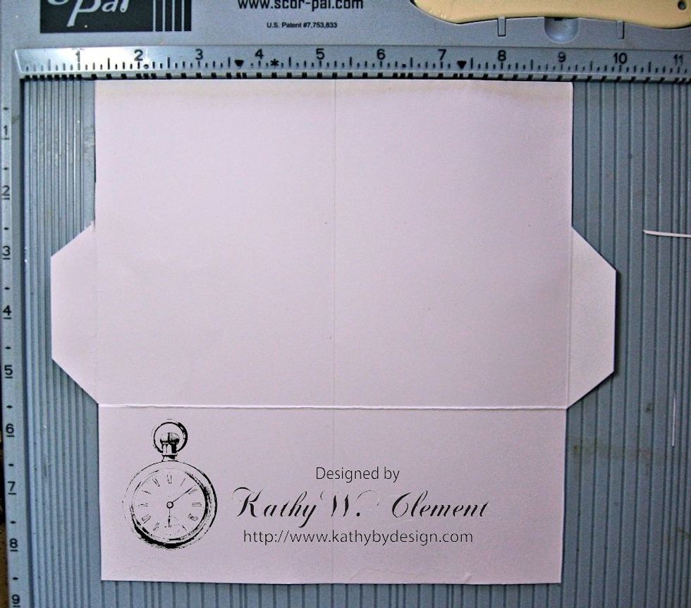 With the long side at the top measure down 2.5" from the top of each side. Cut along the score line, beveling the edge as seen here. Cut from the base to the horizontal score line to form tabs.