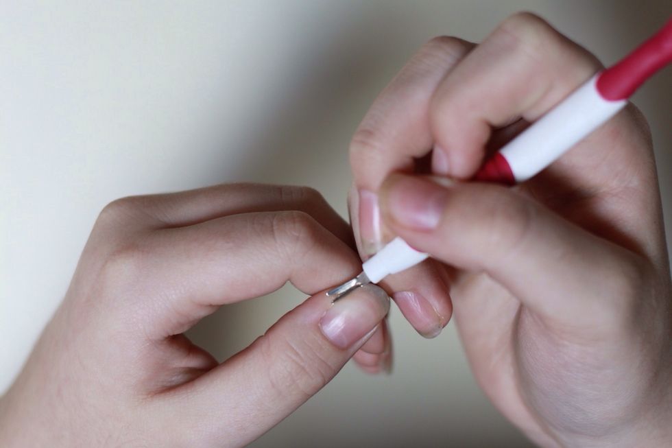 With the metal side of the stick, you are going to gently trim your cuticles.