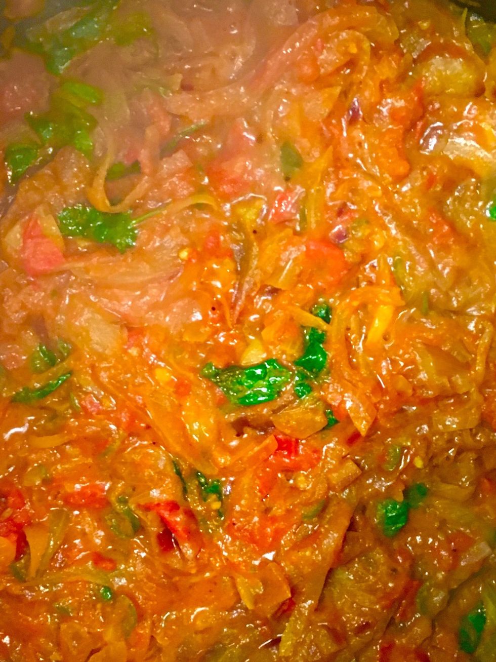 With the onions turning brown, add tomatoes, cilantro, ground cumin, ground coriander and cover until tomatoes are fully cooked.