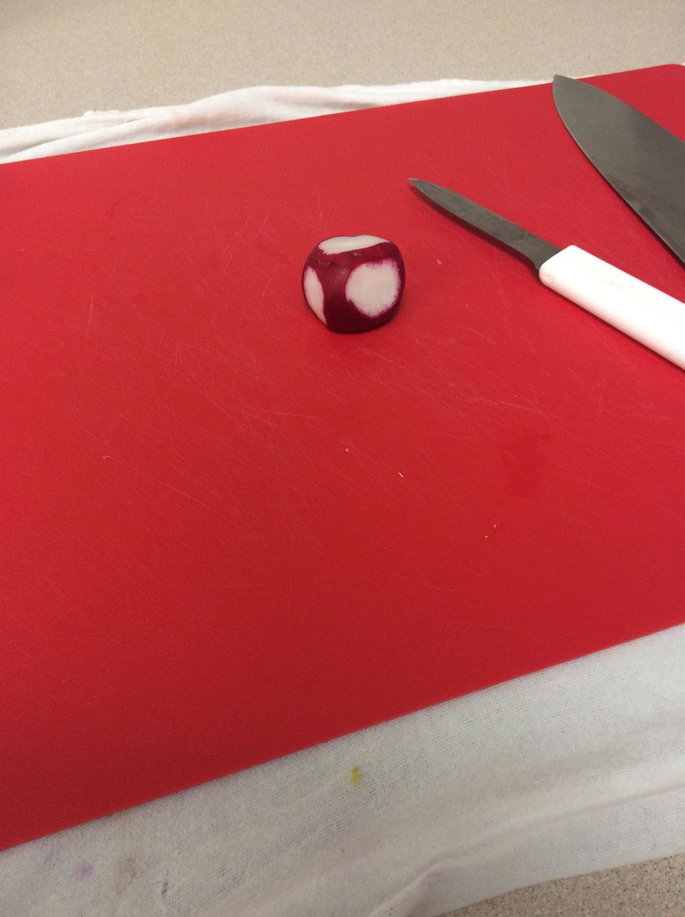 With the paring knife cut off small sections of the skin around the whole radish making sure not to make them too close together and making sure they are not too close to the top or bottom
