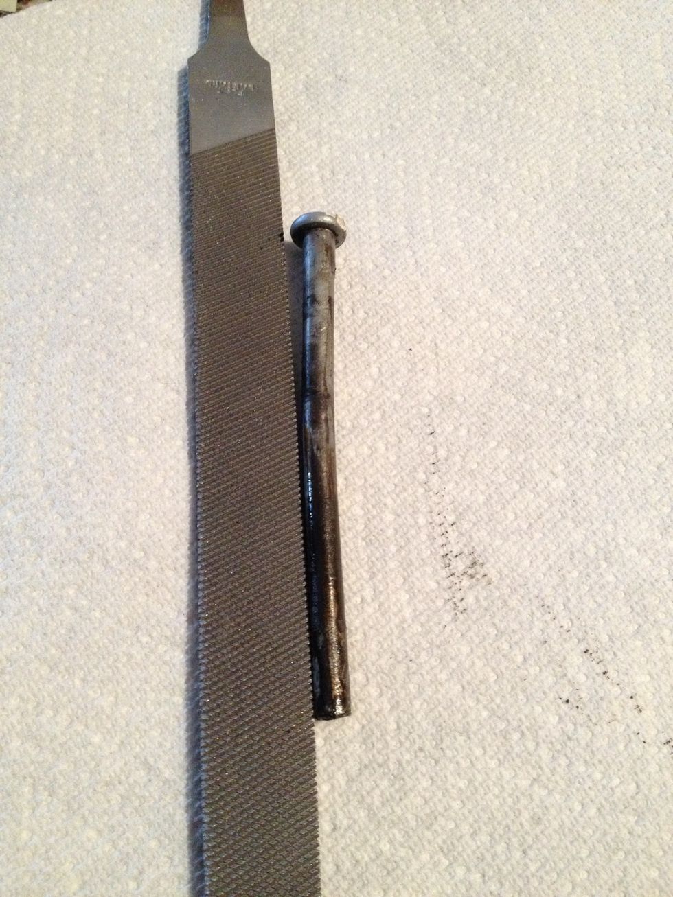 With the pin on a sturdy surface, lightly hammer the middle of the pin to cause it to slightly bend. (File used to show how much the pin is bent, which isn't a lot).