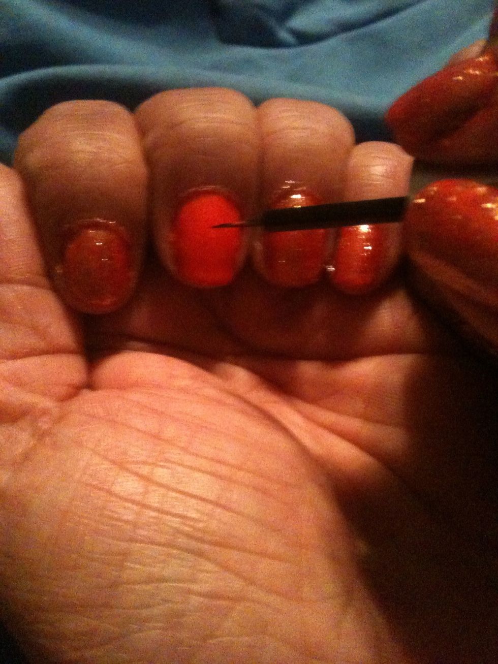 With the thin brush dip it into the black nail polish and begin to draw your pumpkin face.
