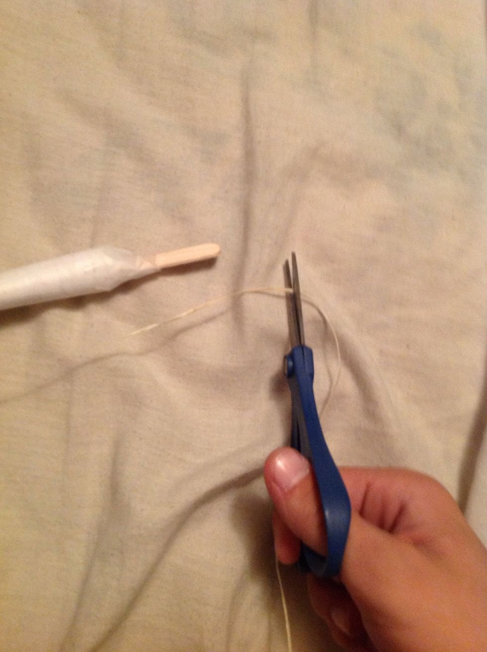 With your ball of twine go about an inch and a half past the other popsicle stick and cut it and tie it around the other end of the popsicle stick.