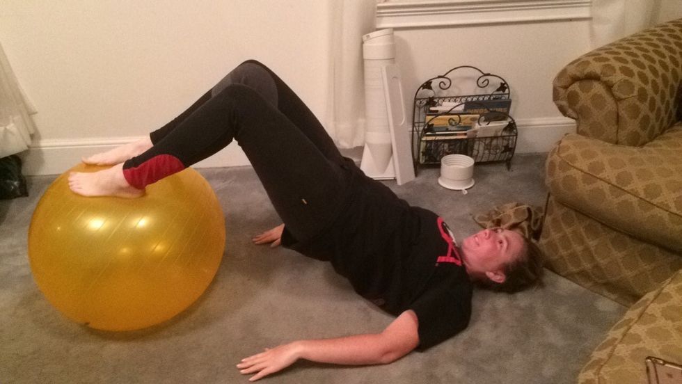 With your feet roll the ball towards you keeping your abdomen tight.