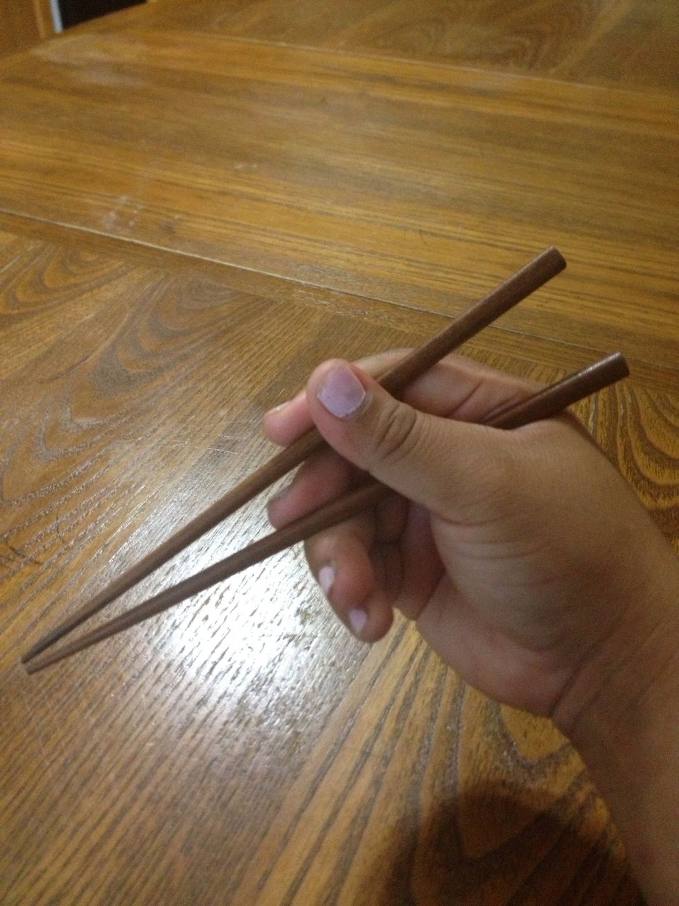 With your middle finger now on the chopstick, you can now insert the second chopstick. With the remaining finger, you place it on top of the chopstick. Like this ---->