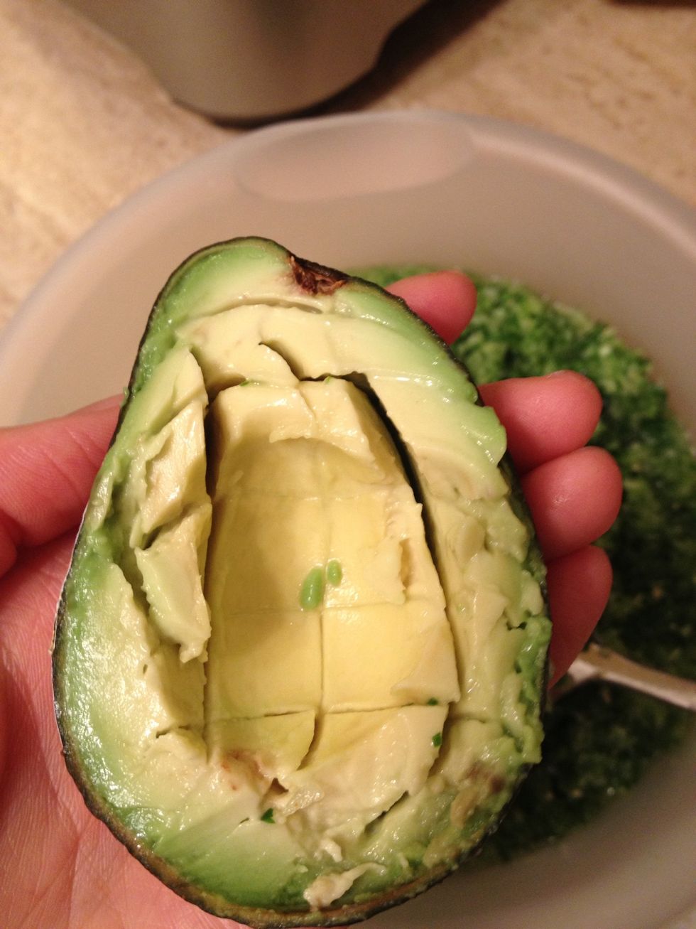 With your spoon, make cuts vertical and then horizontal to create a grid. Then scoop it all out into the salsa.
