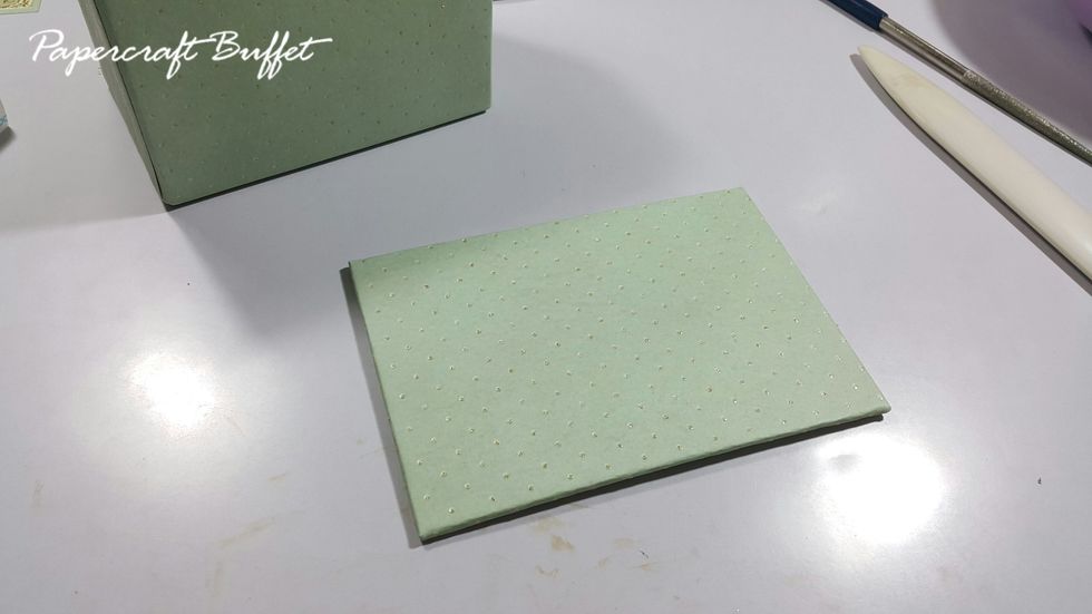 Wrap a piece of chipboard of 4-3/4"x3-1/4" with paper, adhere as the base platform. The basic shape of the stand is finished, you can start decorating with your favorite Maya Road goodies.