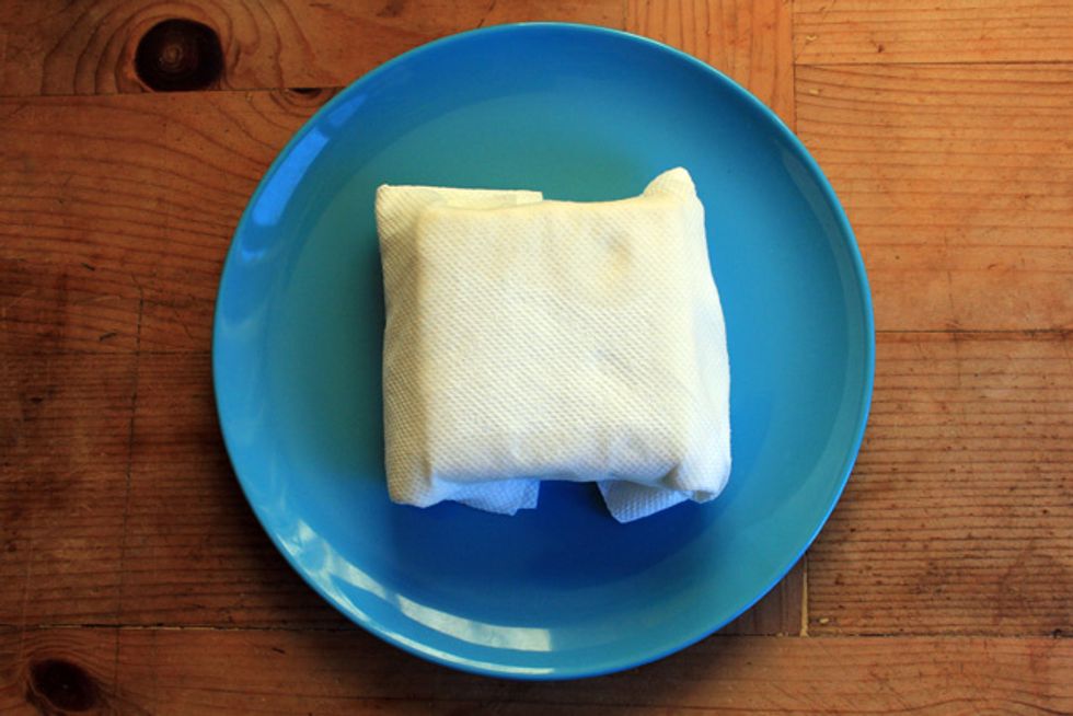 Wrap about 5 layers of paper towels around the block of tofu and let it sit on a plate for 30 minutes. The paper towels will absorb the moisture from the tofu.
