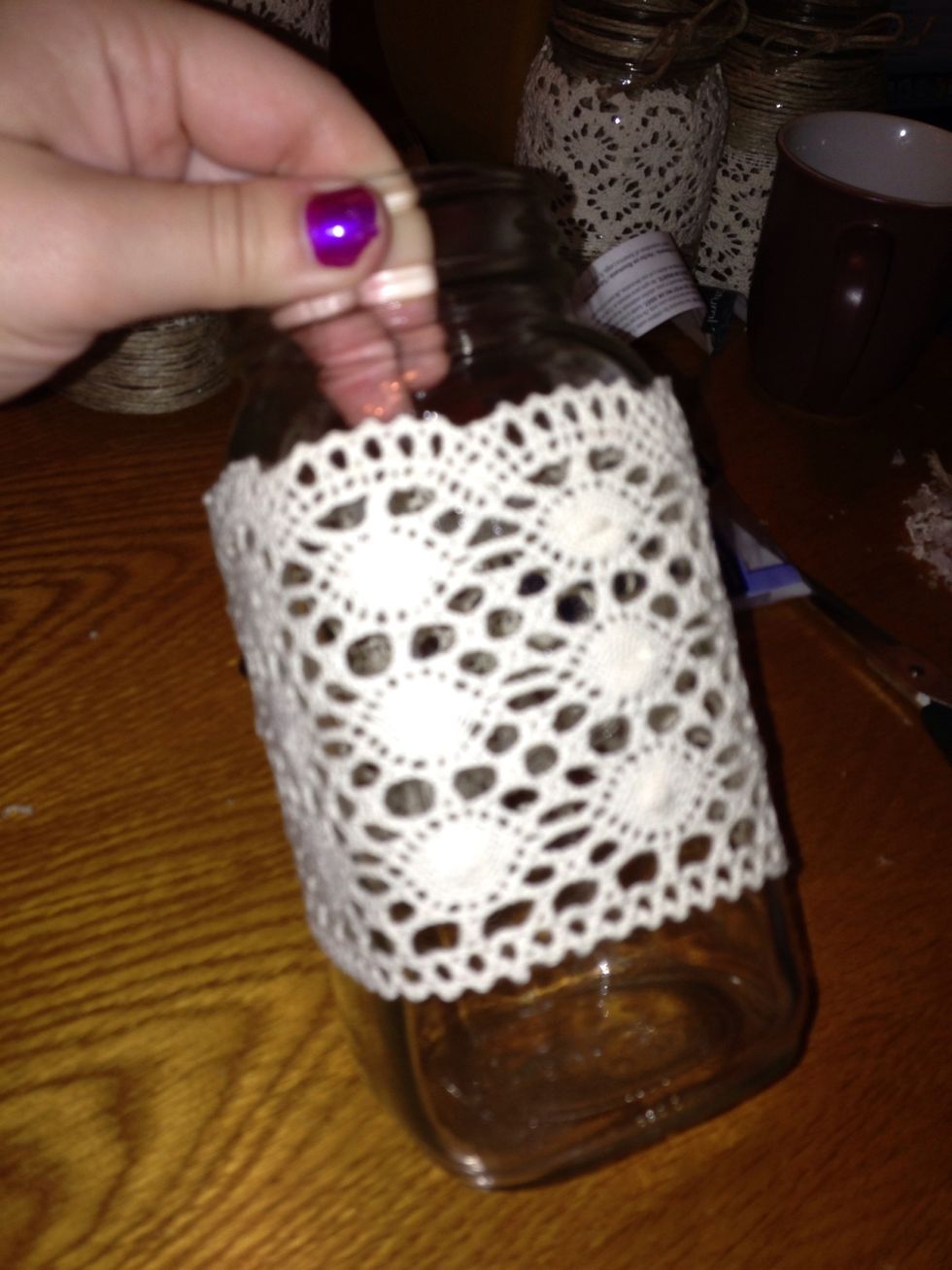 Wrap material around jar while glueing the edges on every side if jar. Make sure to glue it around evenly so that it joins the other side evenly.