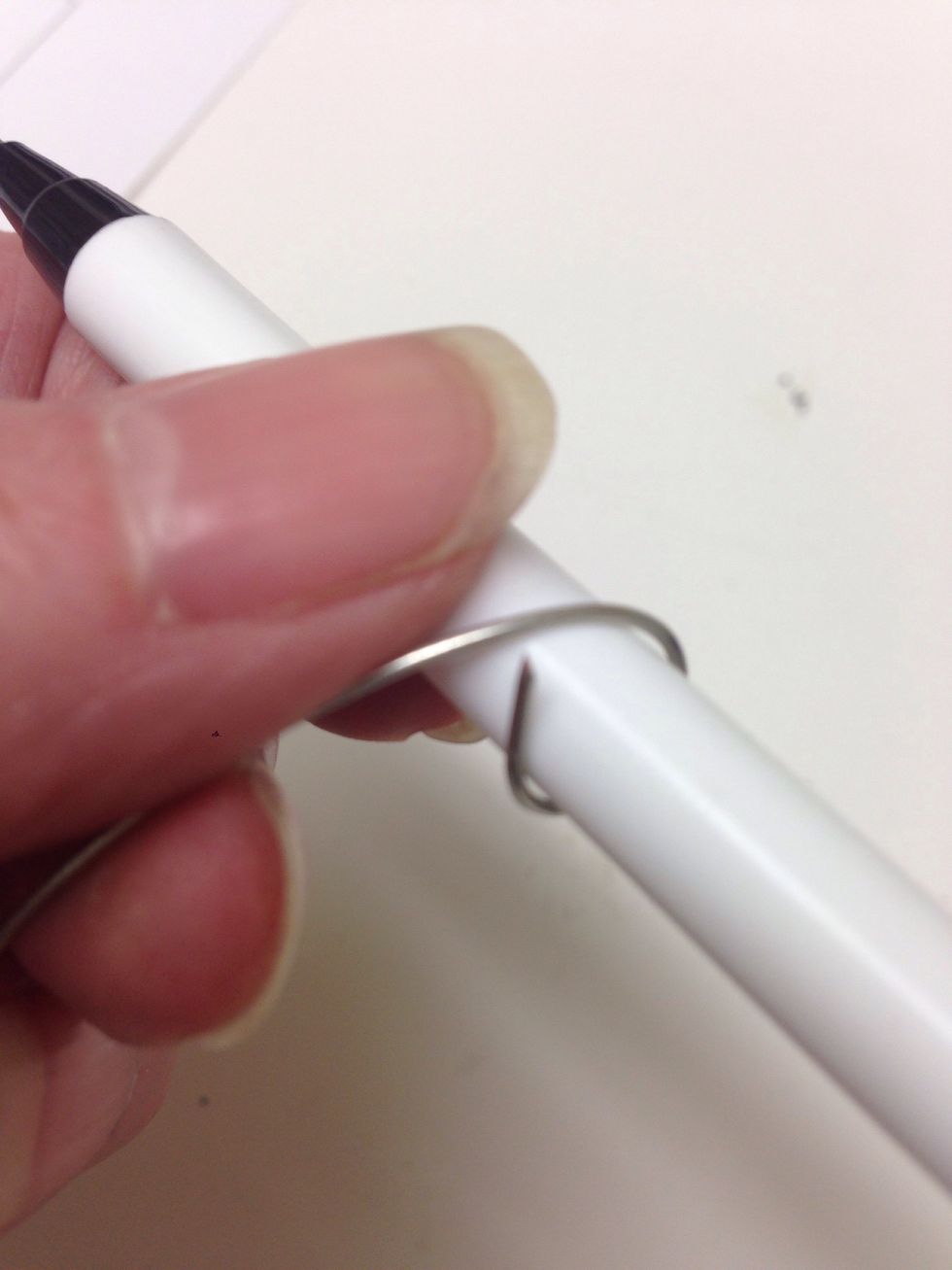 Wrap one end of a wire piece around a pen to start forming the upper portion of your ornament hanger.