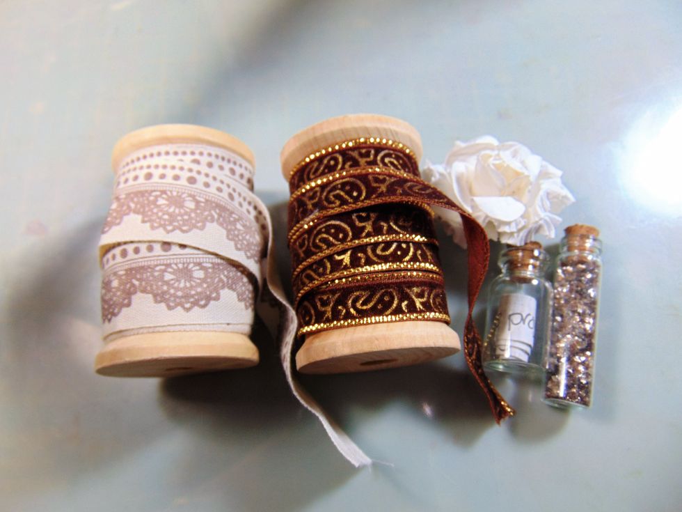 Wrap ribbon around the spools. I put Mica flakes in one bottle and a piece of paper with the date the Hutch was made on in the other. A flower and that was the top shelf complete.