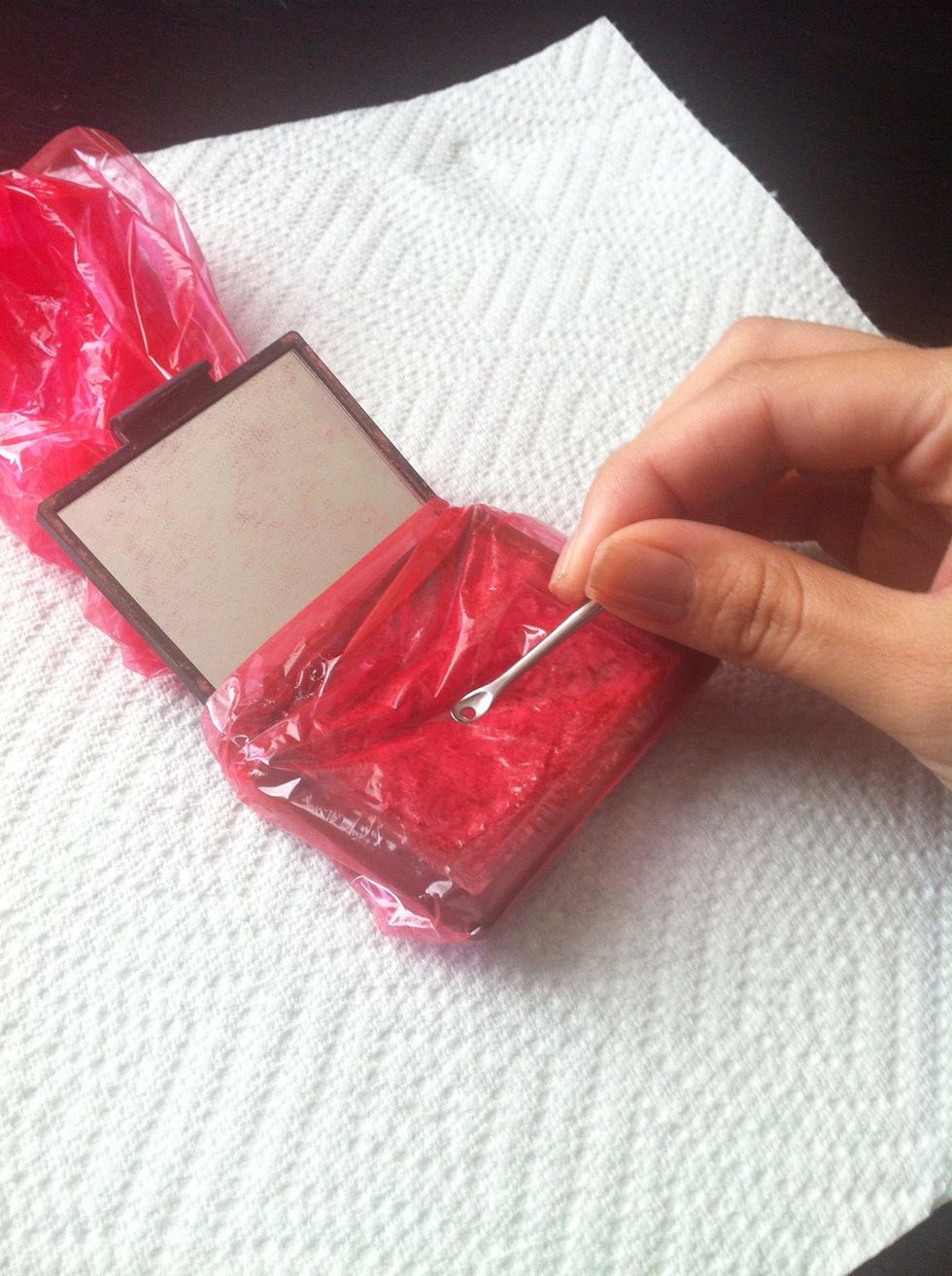 Wrap some plastic wrap around the blush to avoid a mess and begin smashing the blush into a fine powder. Small chunks are okay. You can use any small tool that won't puncture the plastic wrap.