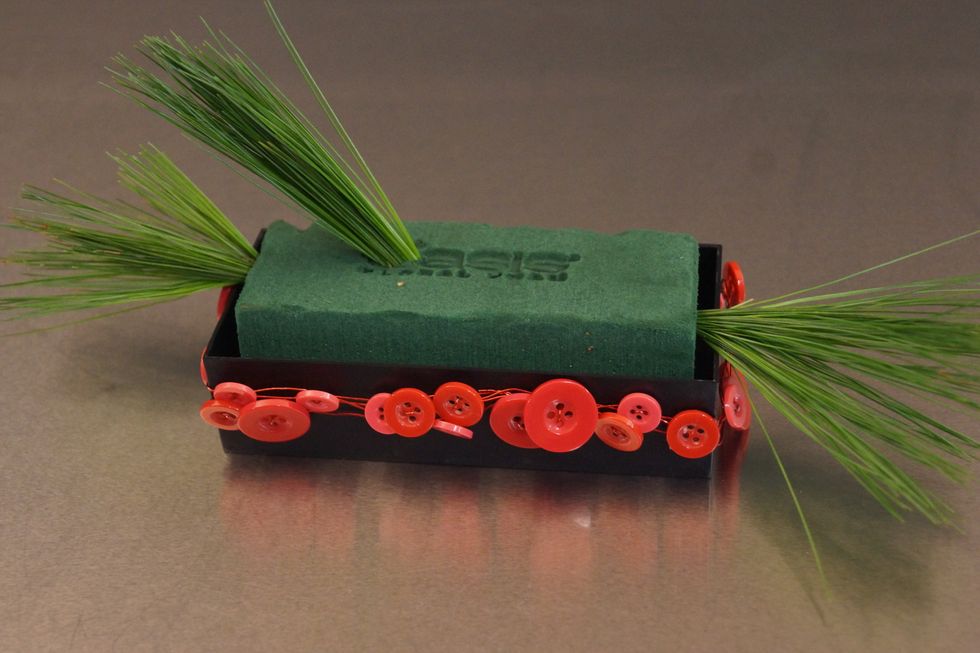 Wrap the container with the button wire. Insert greens on each end, and out the top off-center.