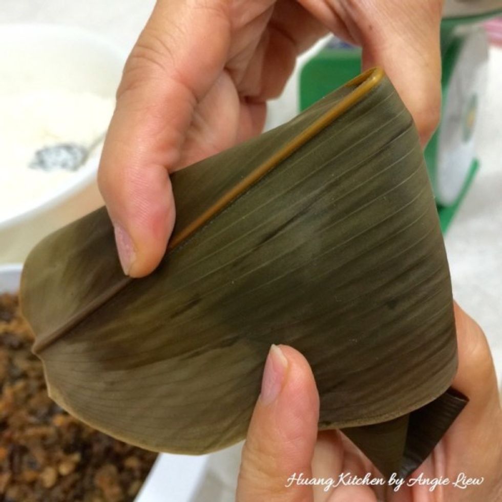 Wrap the edge of the leaves to either left or right side of the rice dumpling. And we're ready to tie it up with a bamboo string.