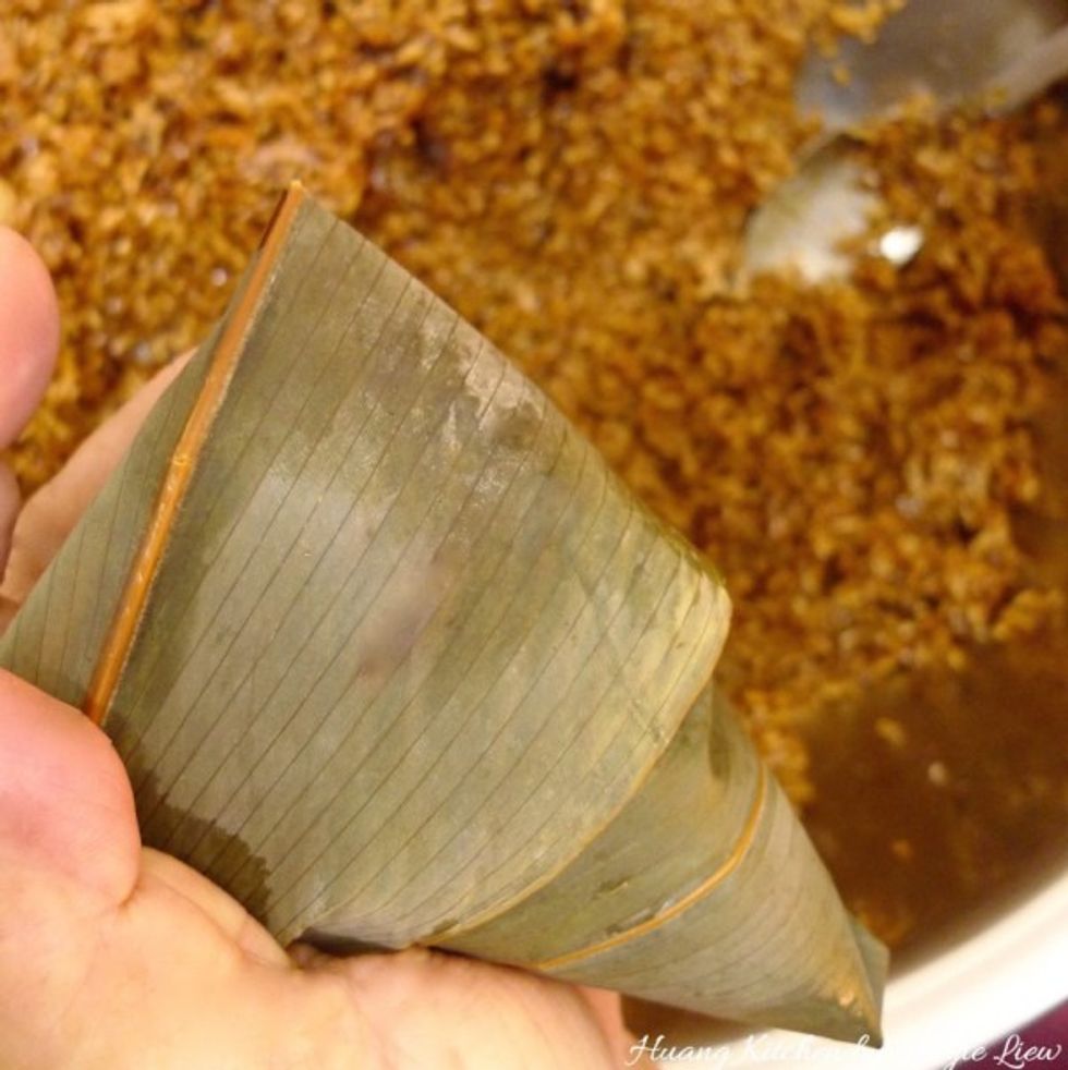 Wrap the edge of the leaves to either left or right side of the rice dumpling. And you're done wrapping it!