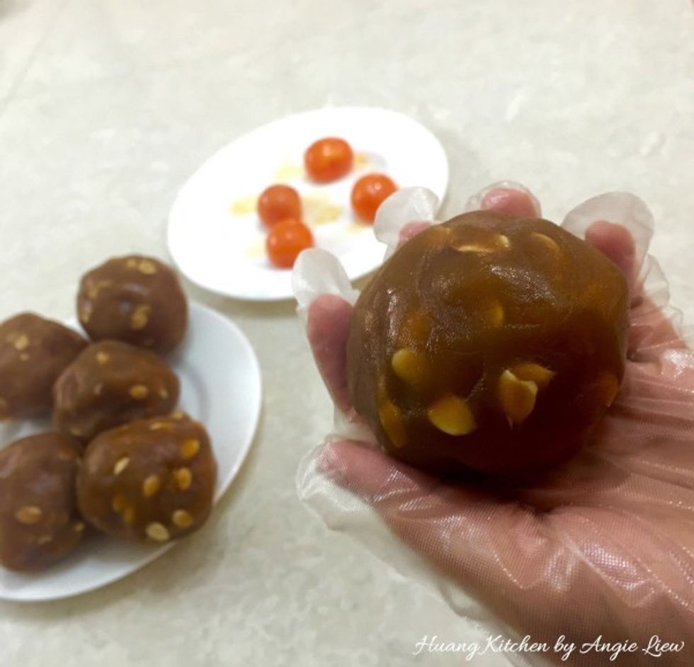 Wrap the egg yolk in the flattened lotus seed paste and roll to form a ball. Repeat for the rest of the lotus seed paste balls. You should get 10 dough balls, each about 135g. Set aside until needed.