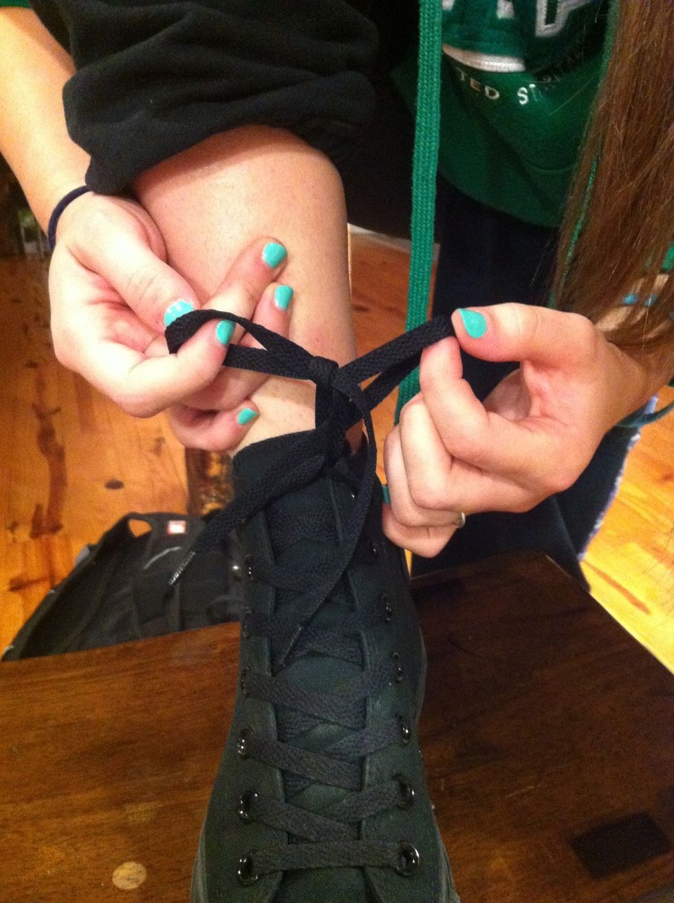 Wrap the other lace around the bottom of the loop, but keep a finger between the loop and the extra string. Then pull the extra string through the hole your finger made, thus creating another loop.