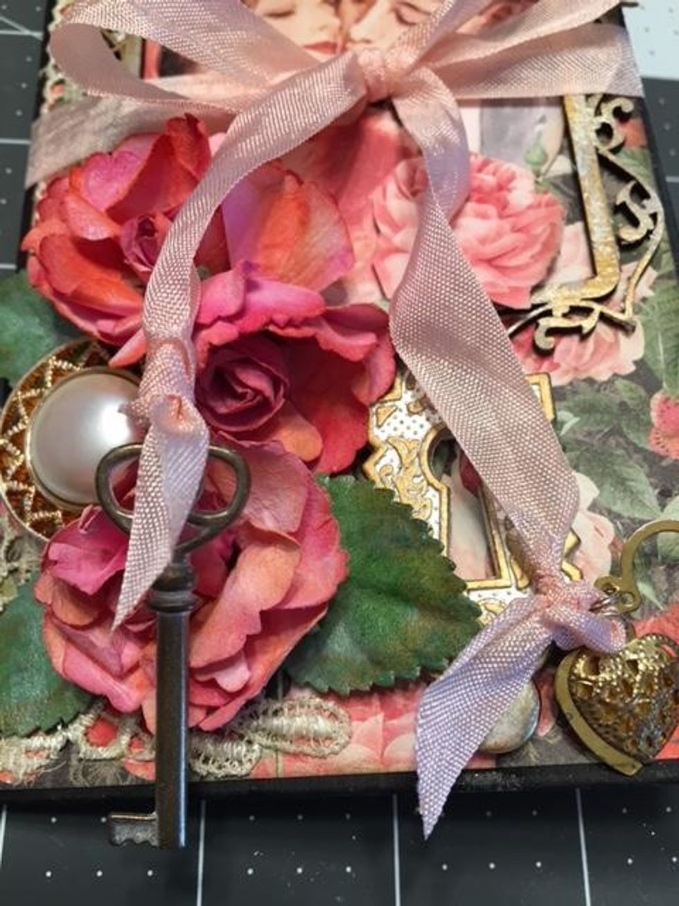 Wrap the ribbon around the booklet and tie into a bow as a closure.  To the ends of the ribbon, tie on a Graphic 45 key and heart charms.