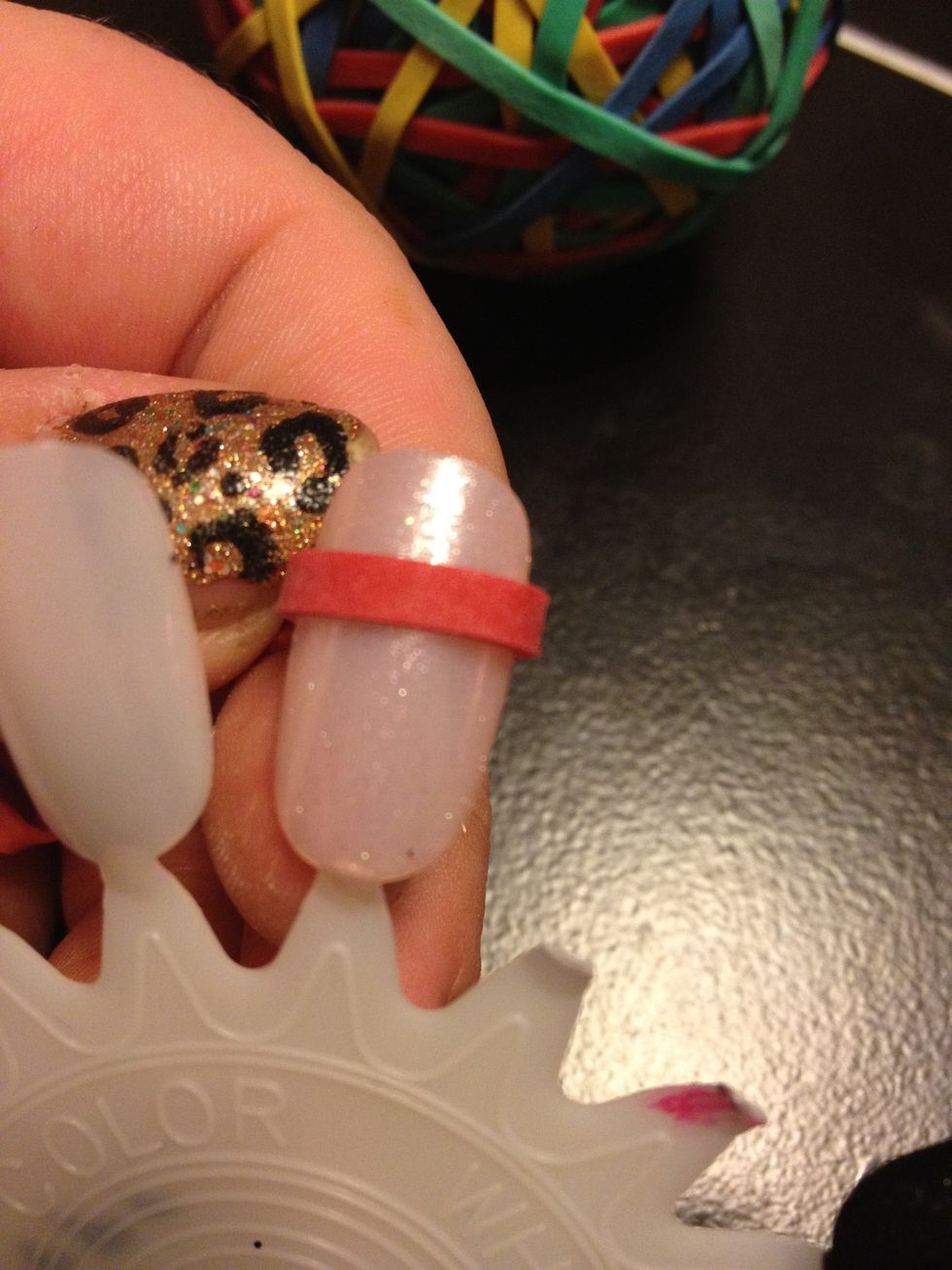 Wrap the rubber band tightly around your finger (mine isn't tight here because it would break the false nail off) Play around with the shape until you see the shape you want your tip to be.