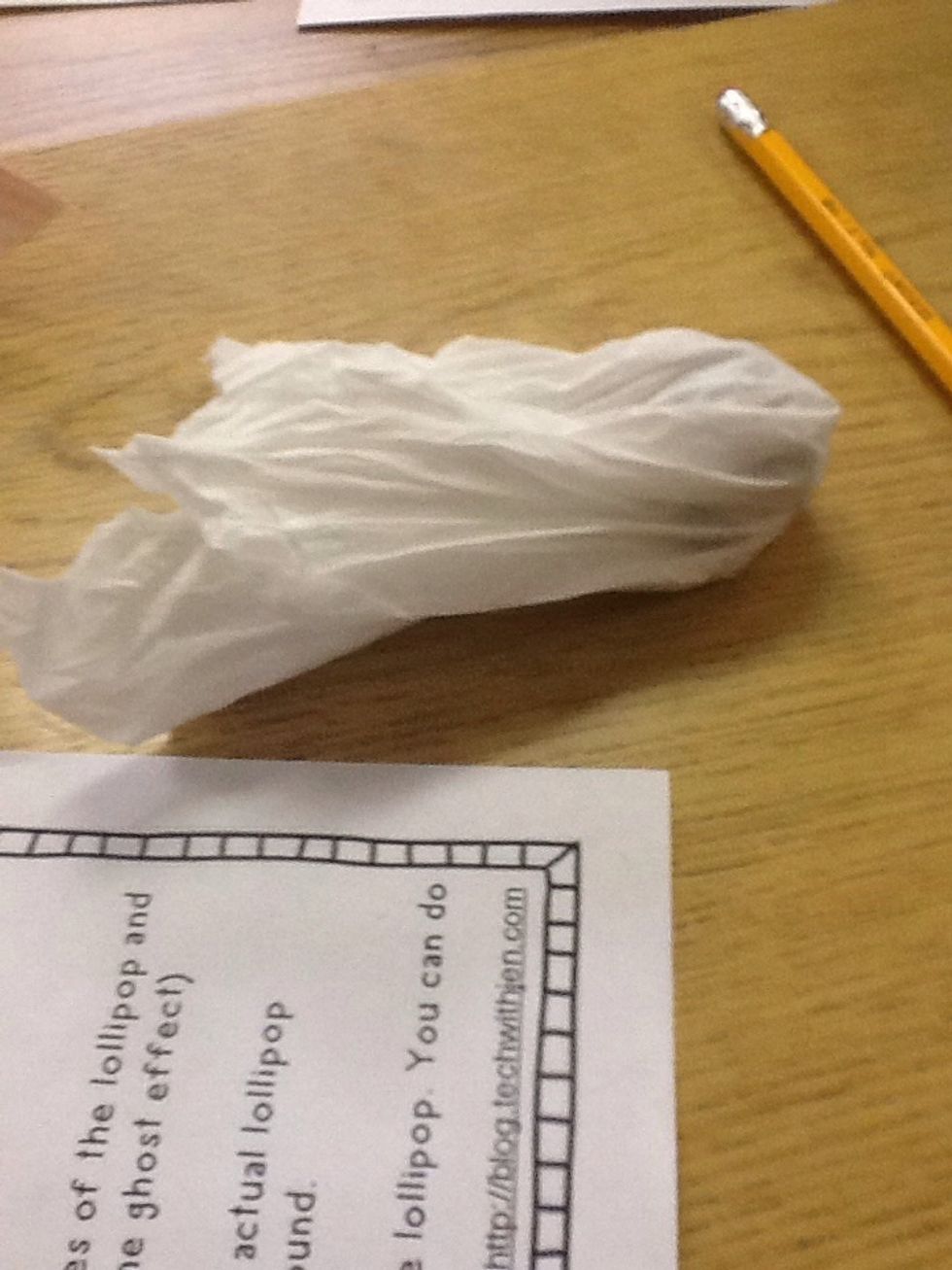 Wrap the tissue around the lollipop so that the colorful wrapping is concealed on both sides.