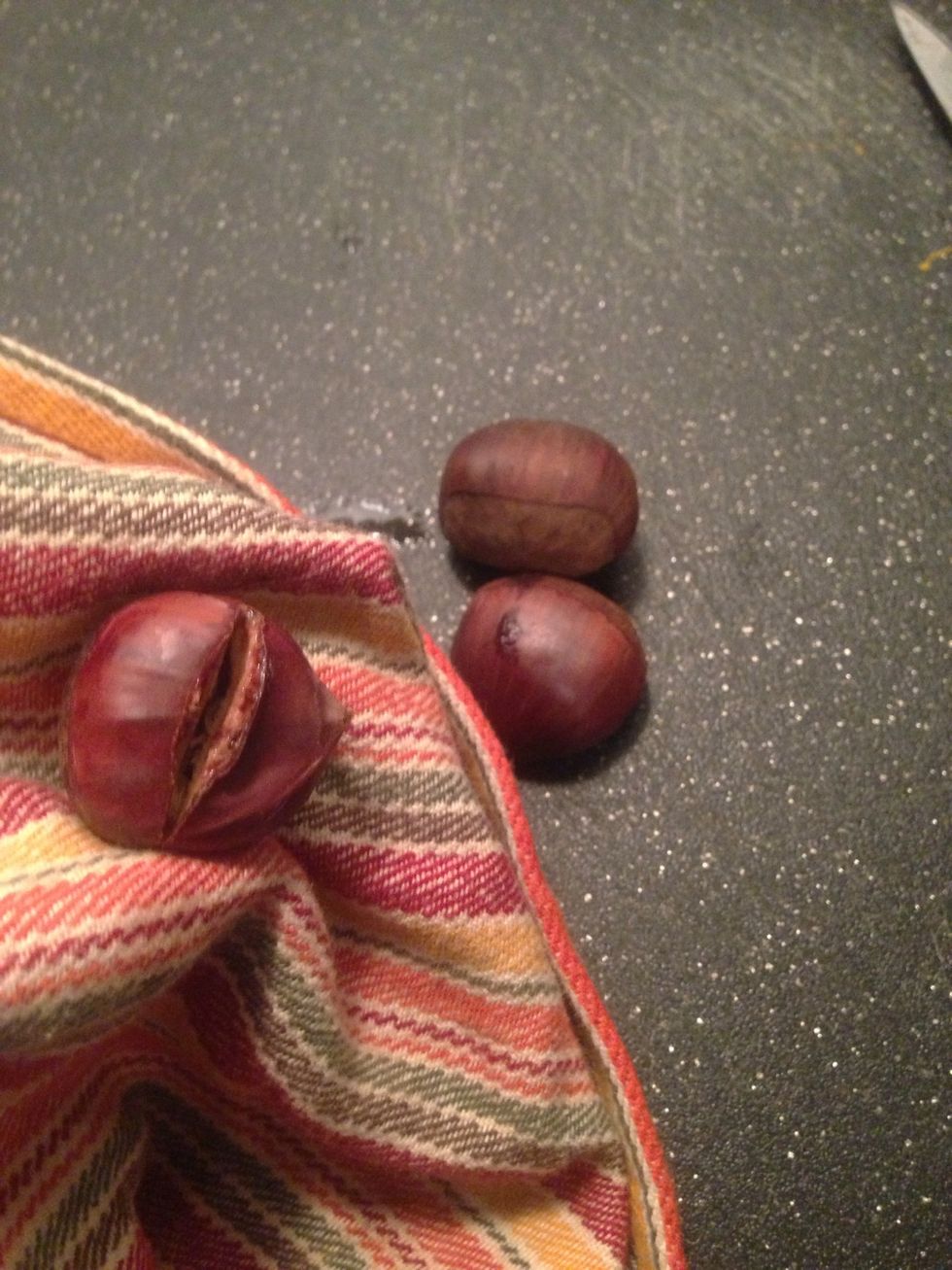 Wrap them in a towel and squeeze them until the skin is crushed. This makes it easier to peel the shell and skin away. Peel both the shell and the skin, once they're cool enough to do so.