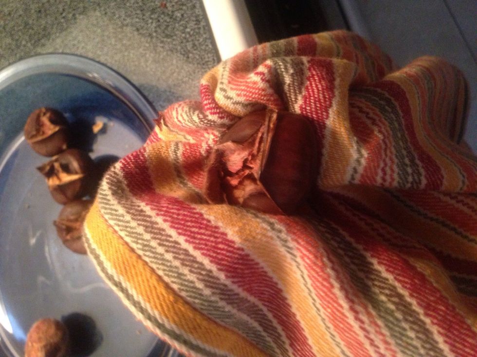 Wrap them in a towel and squeeze them until the skin is crushed. This makes it easier to peel the shell and skin away. Peel both the shell and the skin, once they're cool enough to do so.