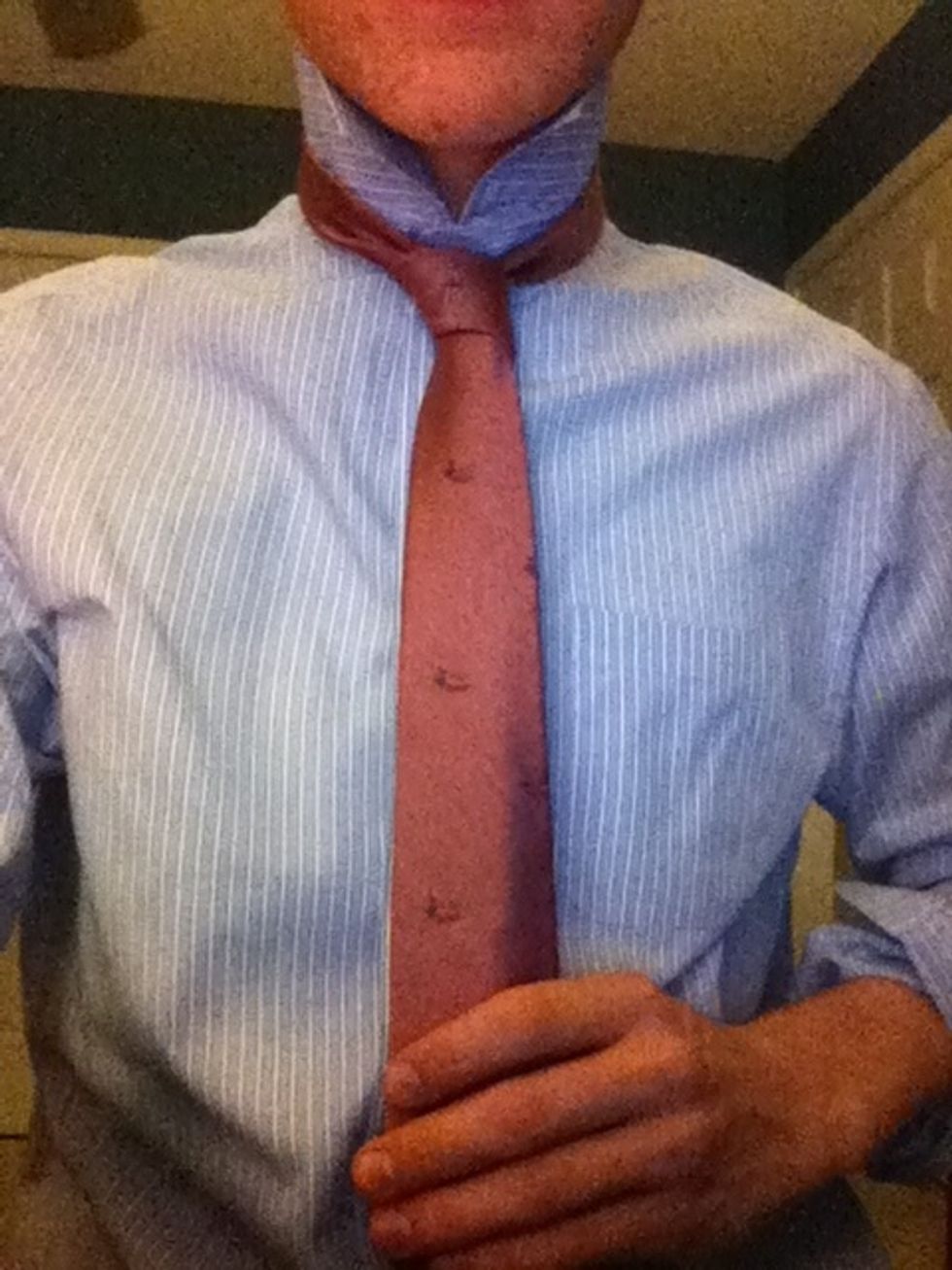 You are done. Tighten the tie by taking hold of the knot near your neck and pulling it up while simultaneously tugging the short, thin piece (hidden by the fat piece) downward.