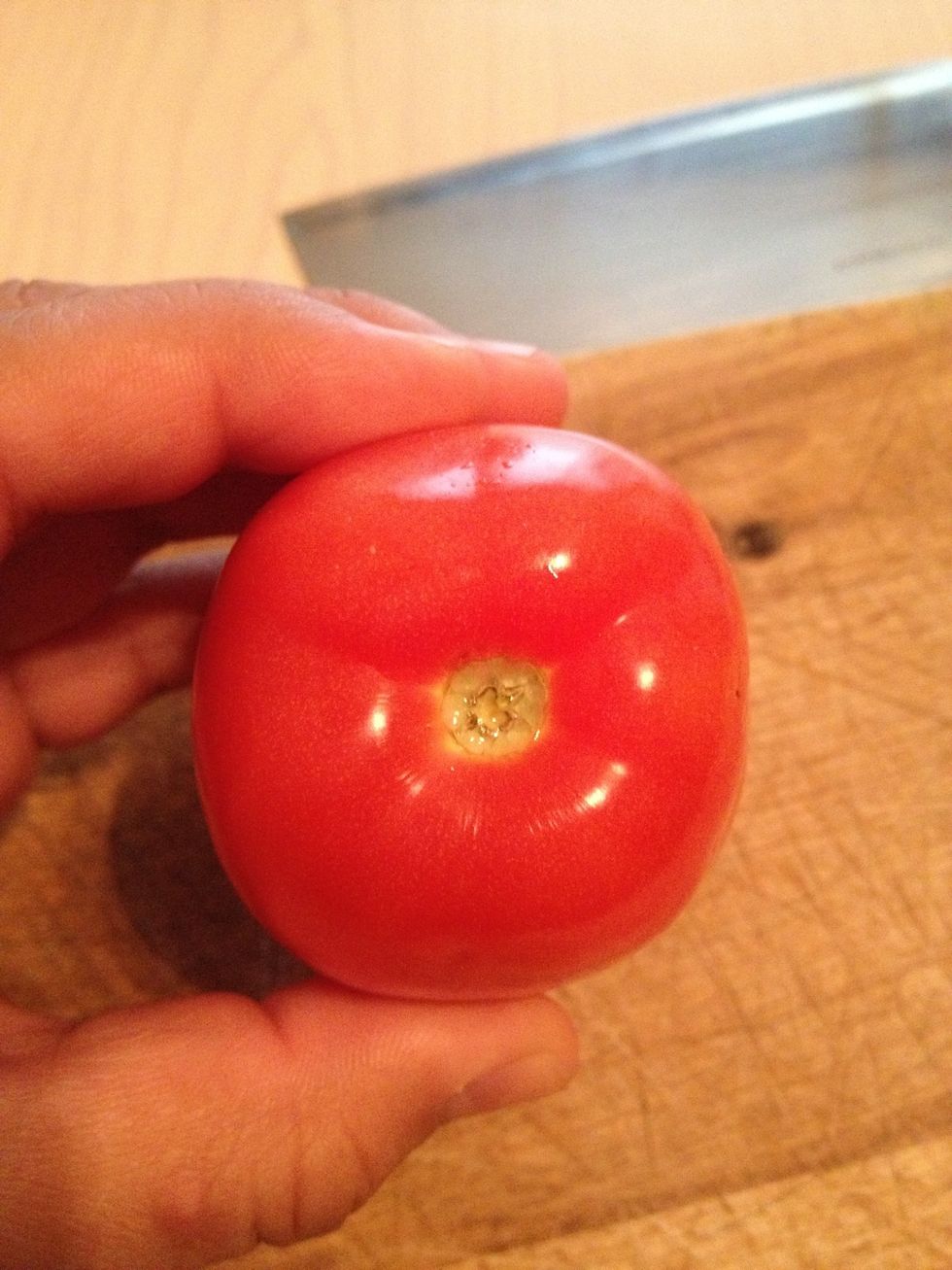 You are going to cut of this end of the tomatoe and discard it.